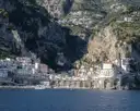 Amalfi’s white houses at the foot of steep cliffs, seen from the water