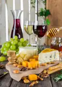 A board of cheese, grapes and crackers with glasses of wine