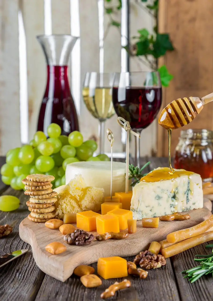 A board of cheese, grapes and crackers with glasses of wine