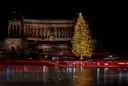 A lit Christmas tree in front of the Vittoriano monument in Rome at night