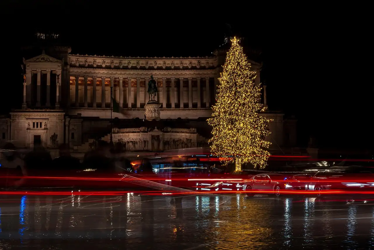 A lit Christmas tree in front of the Vittoriano monument in Rome at night
