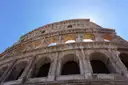 The arches of the Colosseum outer wall against a blue sky