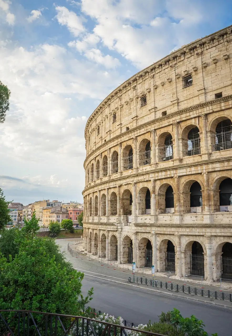 The outer wall of the Colosseum seen from a street with trees