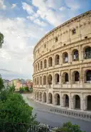 The outer wall of the Colosseum seen from a street with trees