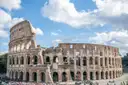 The Colosseum in Rome under a blue sky with white clouds