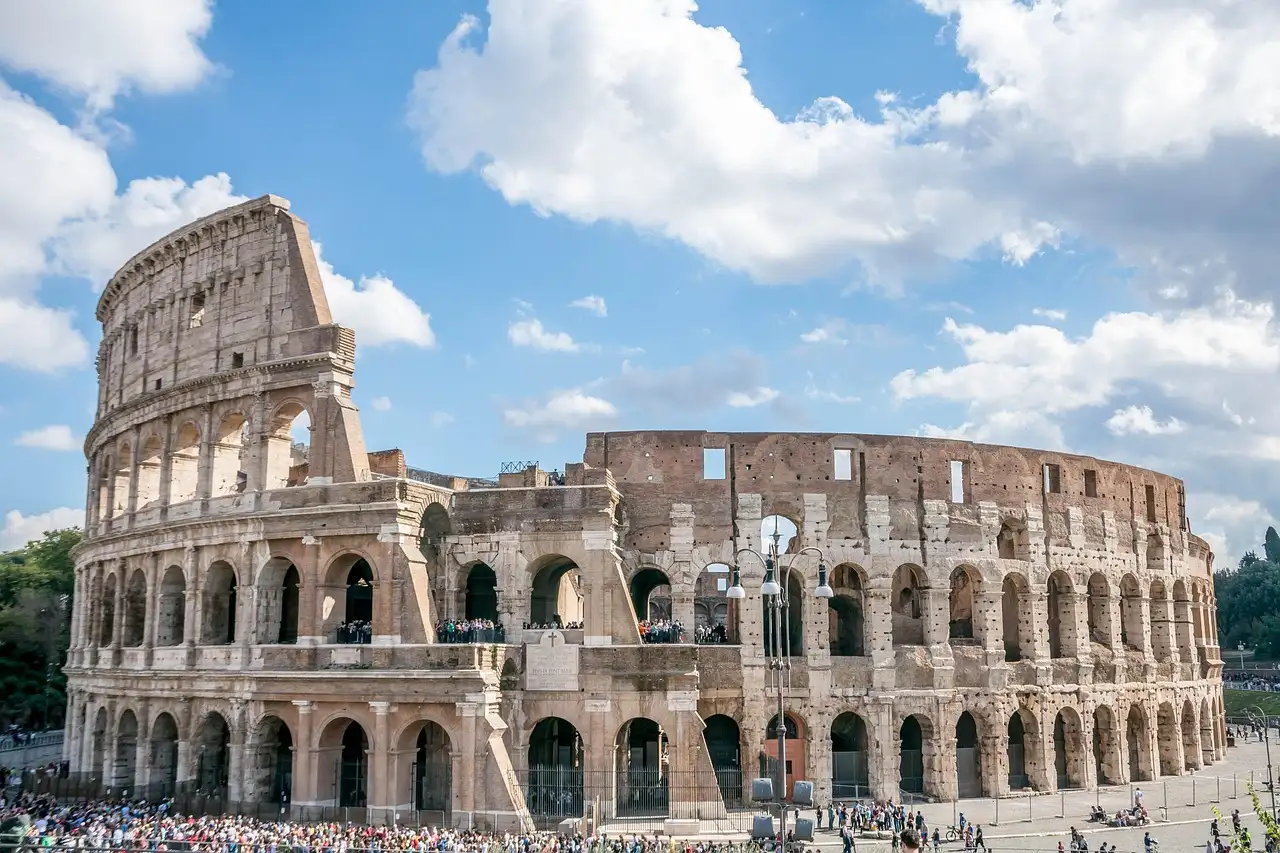 The Colosseum in Rome under a blue sky with white clouds