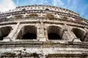 The upper arches of the Colosseum against a blue sky