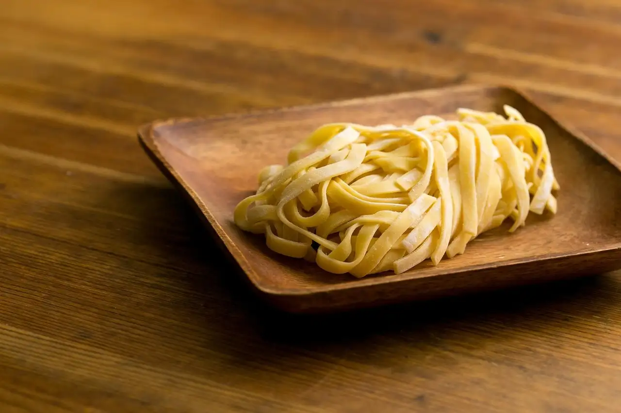 A portion of fettuccine on a square wooden plate