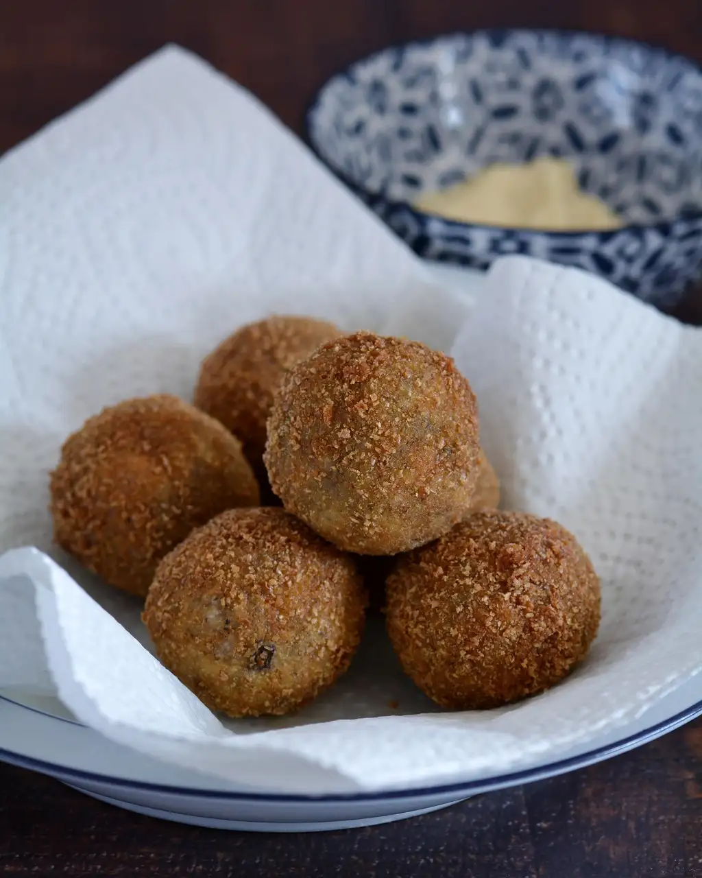 Golden fried rice balls in a bowl lined with a paper napkin