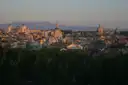 Rome's domes and rooftops at sunset, with mountains on the horizon