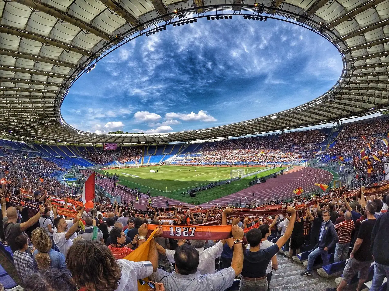 The Stadio Olimpico in Rome during a football match, with fans holding scarves in the stands