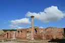 A lone column and brick walls at Ostia Antica under a blue sky