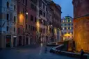 A quiet street in the centre of Rome at dawn, lit by street lamps