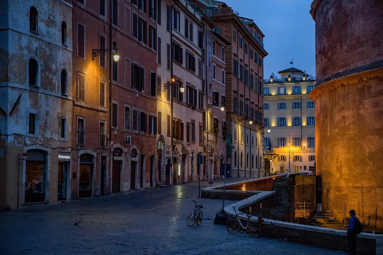 A quiet street in the centre of Rome at dawn, lit by street lamps