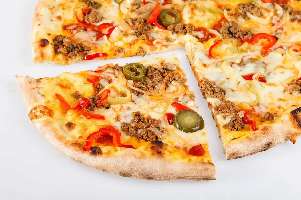 Slices of pizza with olives and peppers on a white surface