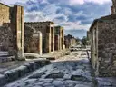 A worn stone street between ruined walls in Pompeii