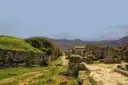 Low ruined walls and an old road in Pompeii, with green hills behind
