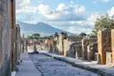 An old paved street in Pompeii with Mount Vesuvius behind it