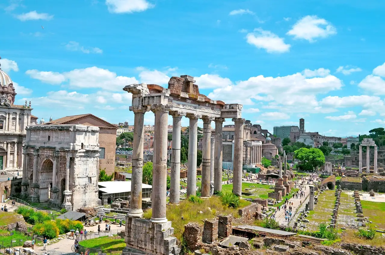 Old temple columns standing in the Roman Forum under a blue sky