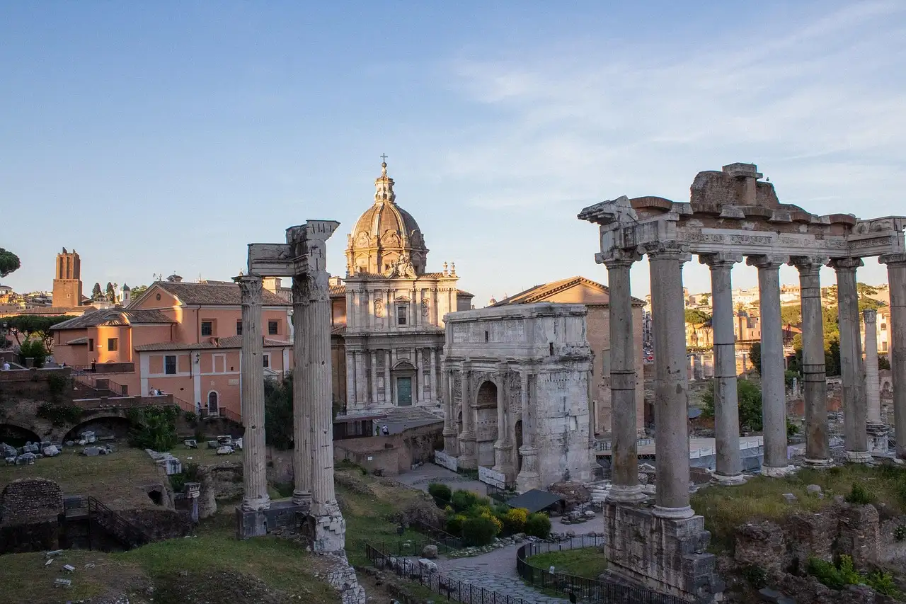 The columns of the Temple of Saturn in the Roman Forum, with a church dome behind