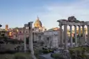The columns of the Temple of Saturn in the Roman Forum, with a church dome behind
