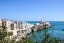 A white clifftop town above a blue sea on the coast of Puglia in southern Italy