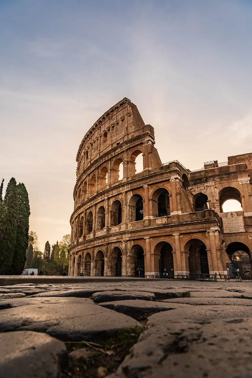 The Colosseum in Rome at sunset, seen from the old stone paving in front of it