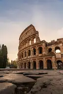The Colosseum in Rome at sunset, seen from the old stone paving in front of it