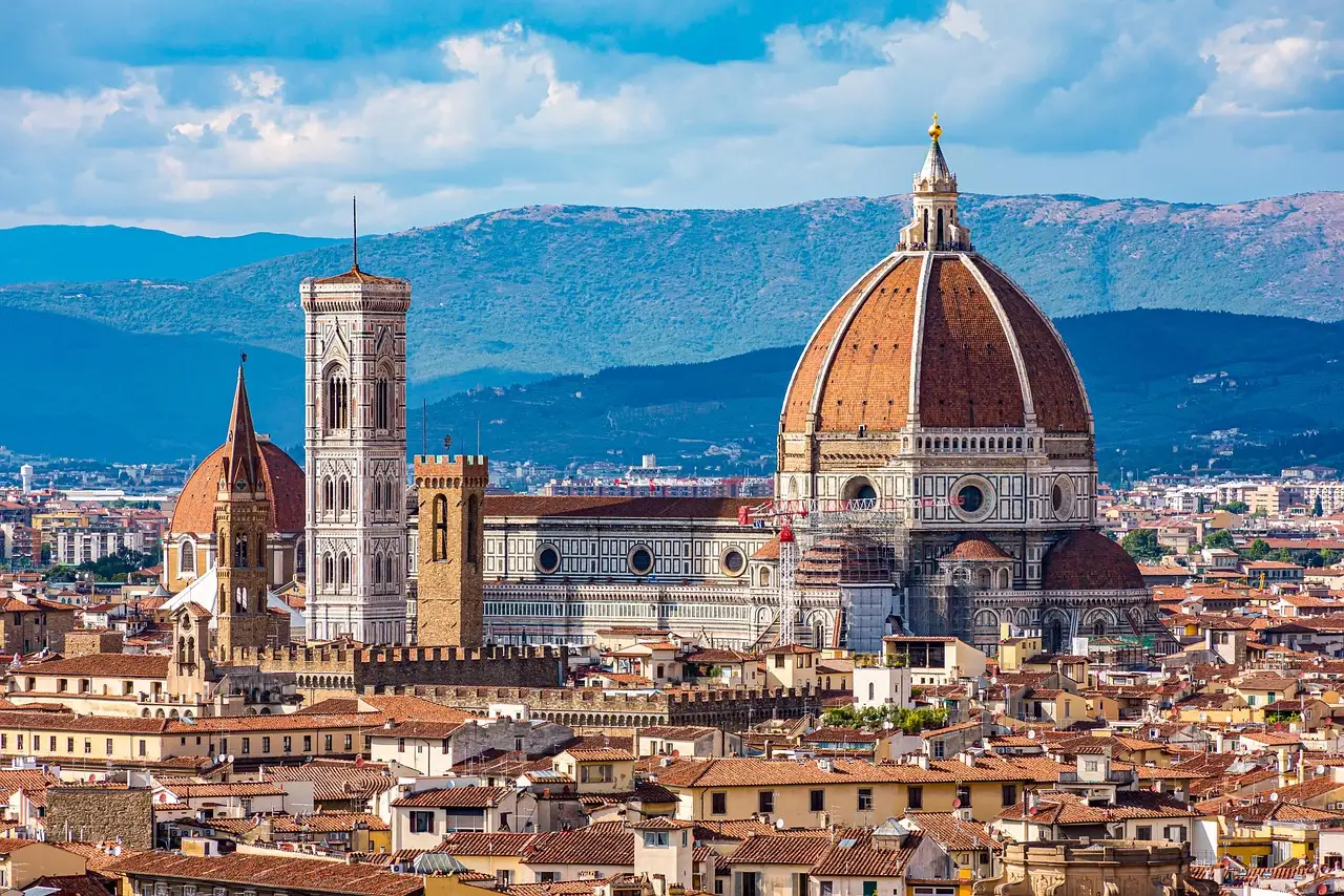 View over Florence rooftops to the cathedral dome and bell tower, with hills behind
