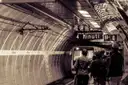 A Rome metro train pulling into a platform, with a sign showing the next train in 4 minutes