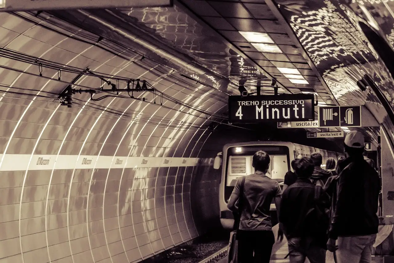 A Rome metro train pulling into a platform, with a sign showing the next train in 4 minutes