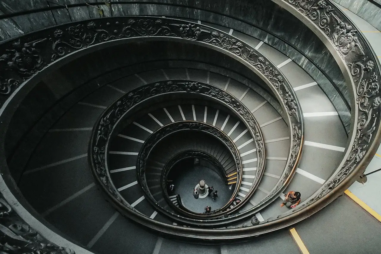 Looking down a spiral staircase with a double ornate railing