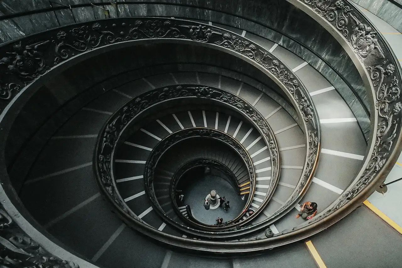 Looking down a spiral staircase with a double ornate railing