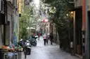A narrow street in the old centre of Naples, with scooters, shops and people walking