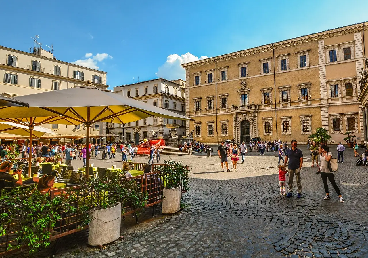 Café tables and people on the cobbled square of Santa Maria in Trastevere, Rome