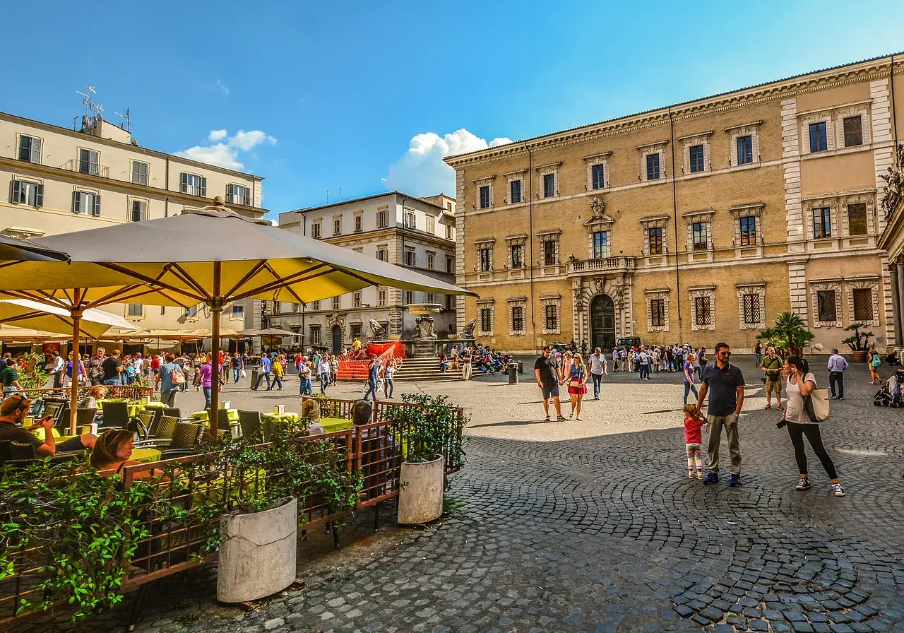 Café tables and people on the cobbled square of Santa Maria in Trastevere, Rome