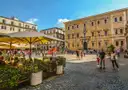 Café tables and people on the cobbled square of Santa Maria in Trastevere, Rome
