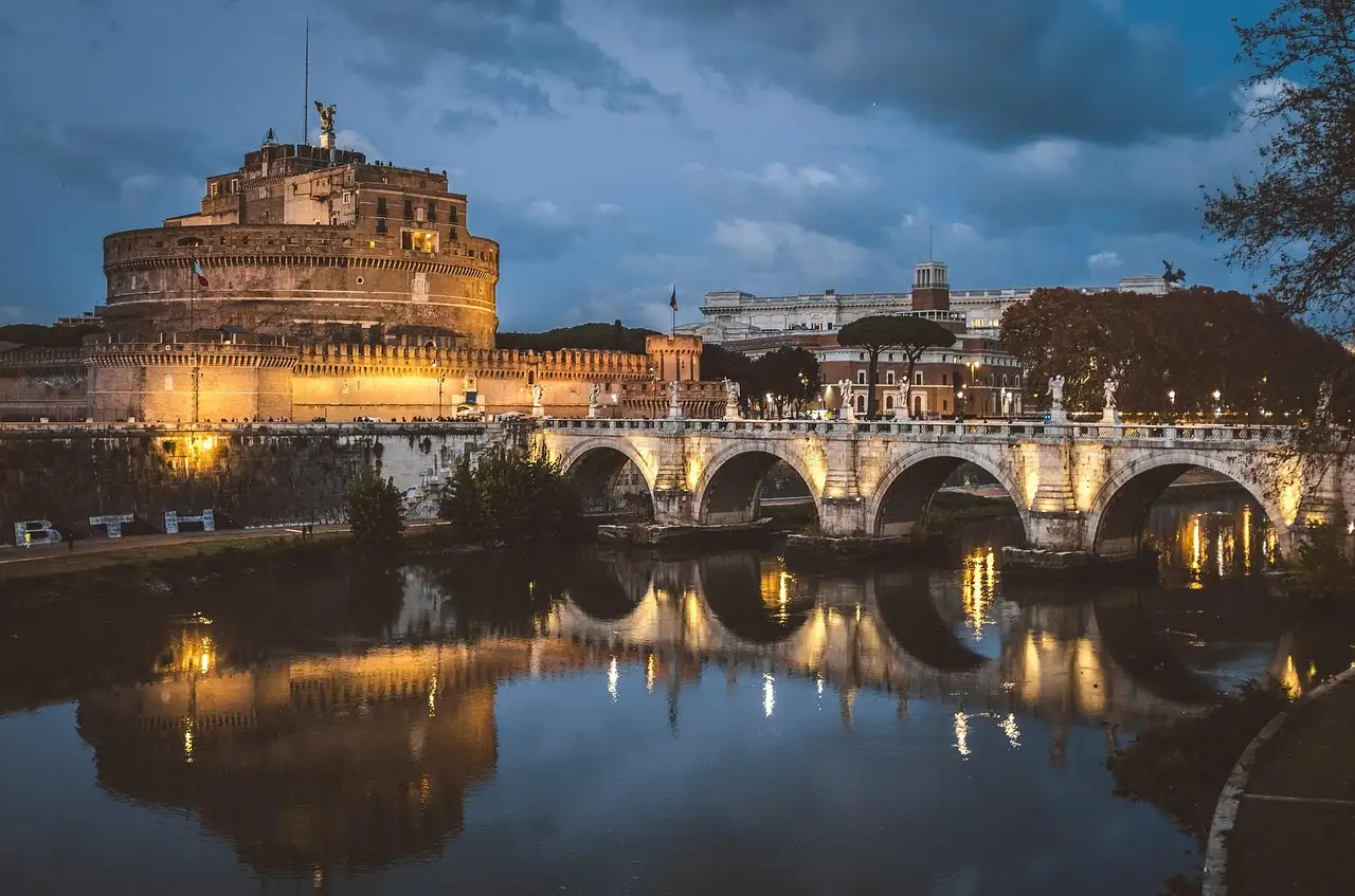 Castel Sant'Angelo and its bridge lit up over the Tiber in Rome at dusk