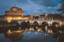 Castel Sant'Angelo and its bridge lit up over the Tiber in Rome at dusk