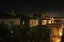 Old Rome rooftops and a terrace lit by street lamps at night