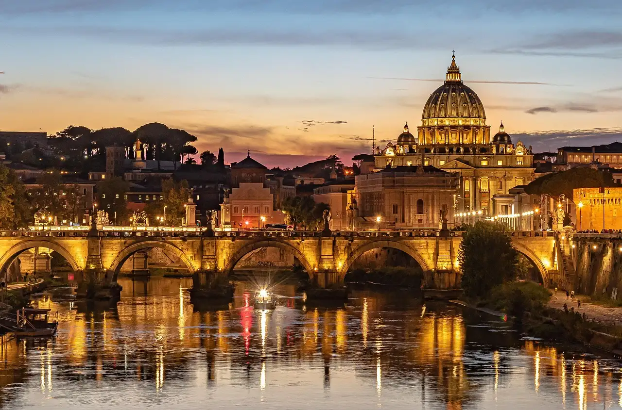 St. Peter's dome and a lit bridge over the Tiber at dusk