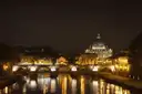 St. Peter's dome and a bridge over the Tiber lit up at night