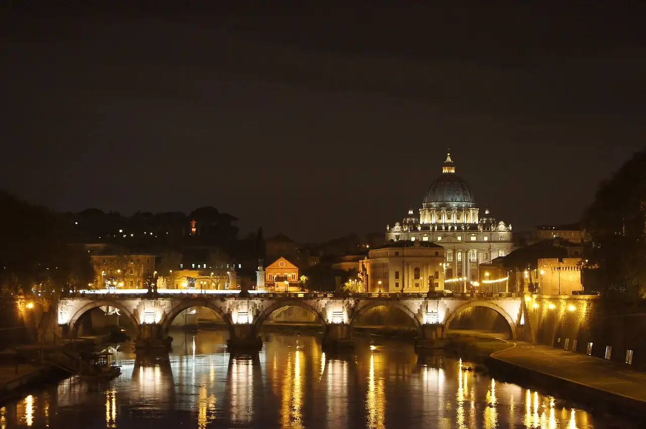 St. Peter's dome and a bridge over the Tiber lit up at night