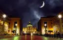Via della Conciliazione and St. Peter's Basilica lit at night under a crescent moon