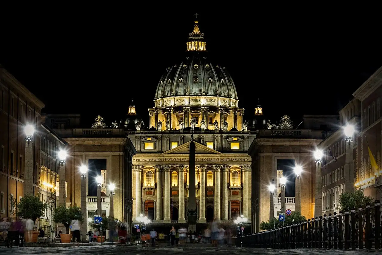 St. Peter's Basilica lit up at night, seen down the street