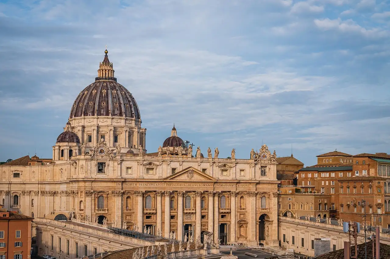 The front and dome of St. Peter's Basilica under a cloudy sky