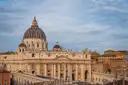 The front and dome of St. Peter's Basilica under a cloudy sky