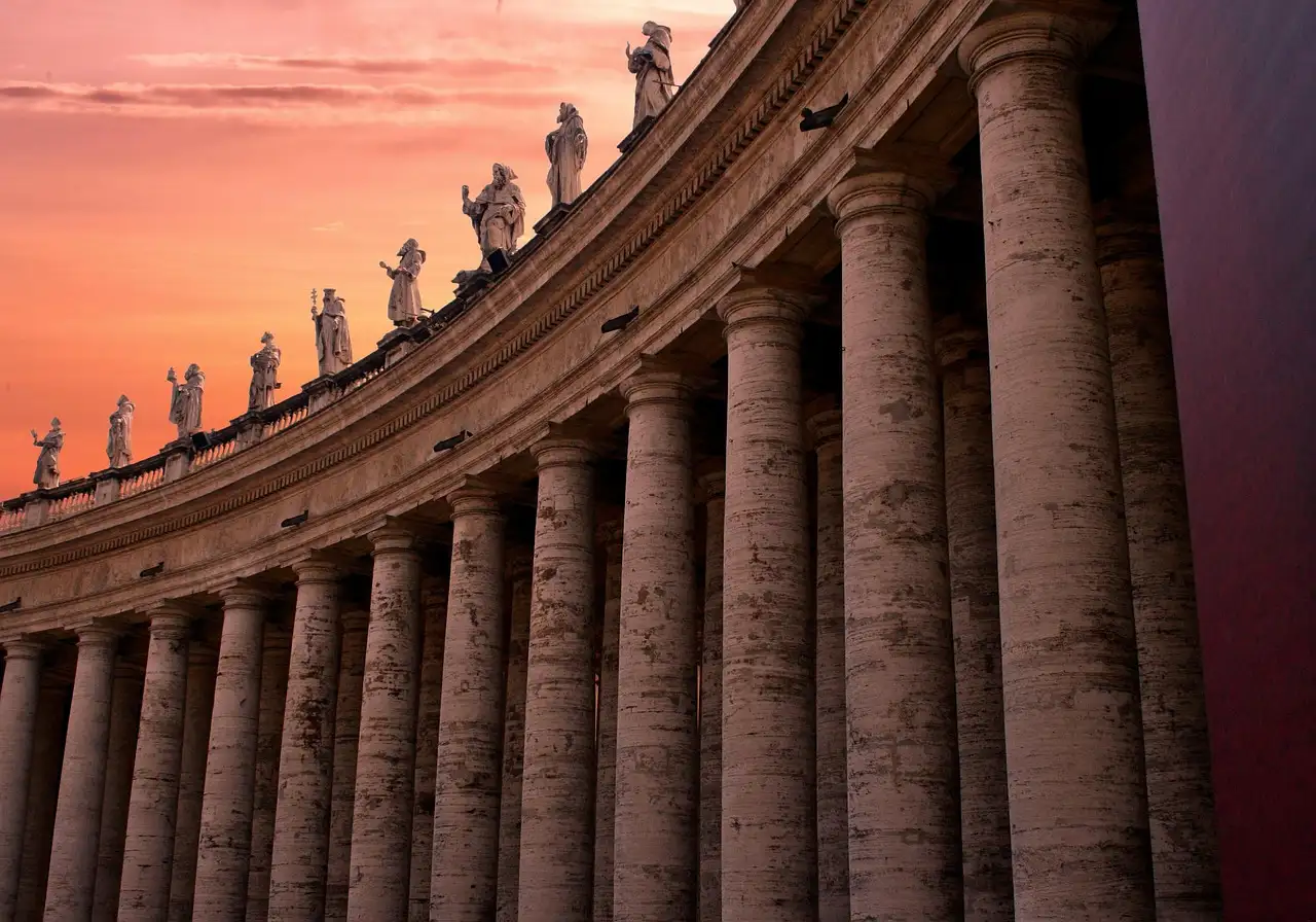 The columns and statues of St. Peter's Square colonnade at sunset