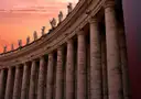 The columns and statues of St. Peter's Square colonnade at sunset