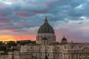 The dome of St. Peter's Basilica against a pink and grey evening sky